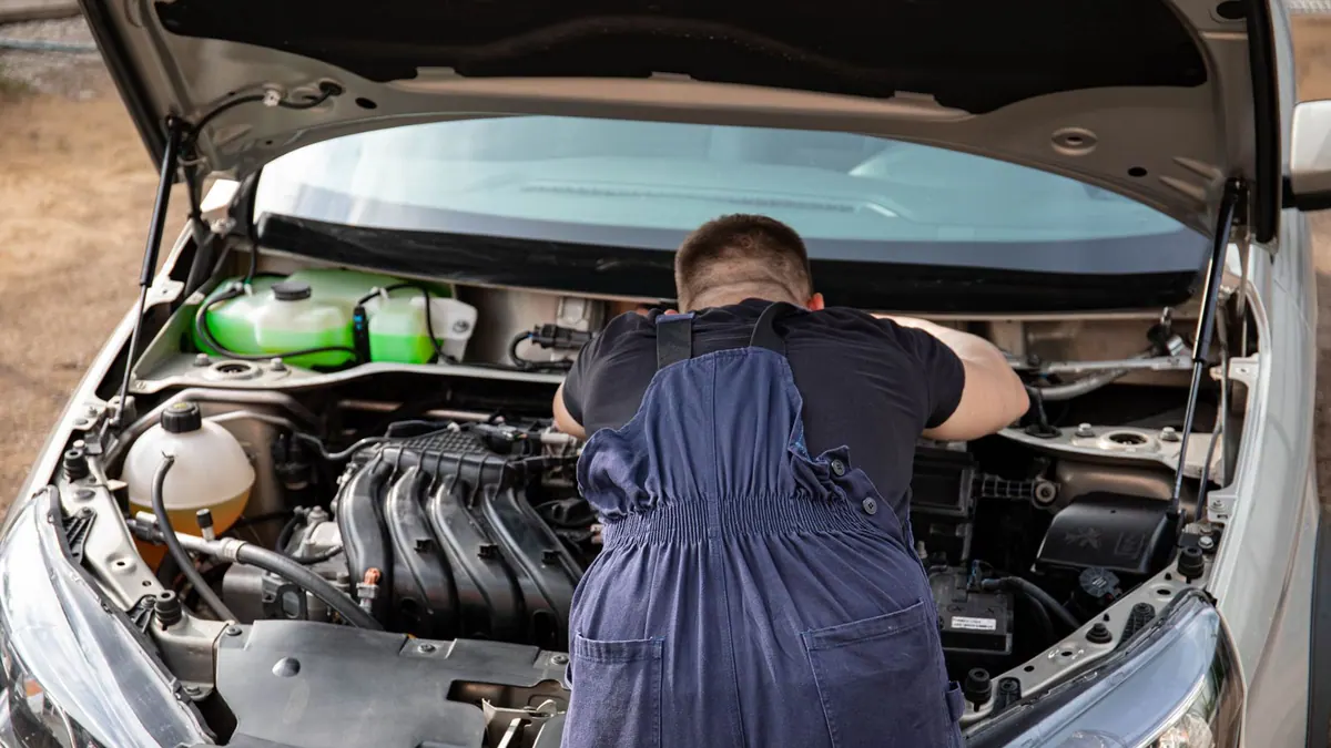 Mécanicien en bleu de travail réparant un moteur en extérieur